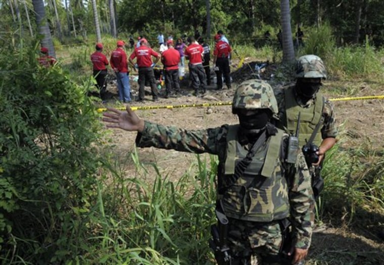 Mexican Navy soldiers guard the perimeter as civil protection and forensic workers search for bodies buried at a field in the town of Tuncingo, southern Mexico on Wednesday, Nov. 3, 2010. 